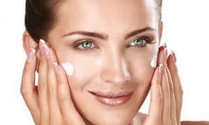  a woman lubricates her face with a cream